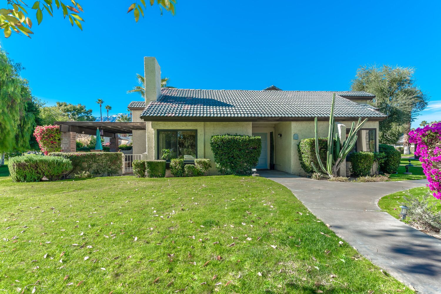 A two-story building with a tiled roof, a front entrance, and a well-maintained lawn.