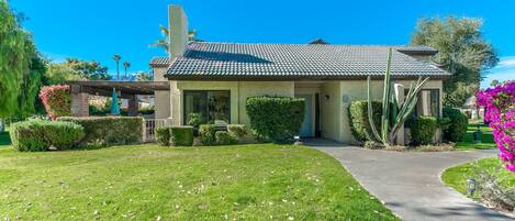 A two-story building with a tiled roof, a front entrance, and a well-maintained lawn.
