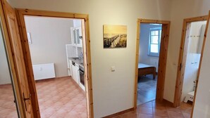 A room with a tiled floor, a bed, a window, and a painting on the wall. - Vacation apartment Strandwiese 3 (Graal-Müritz)