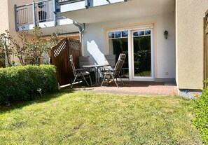A patio with a table and chairs, a wooden gate, and a sliding glass door. - Strandwiese 3 Vacation Apartment (Graal-Müritz)