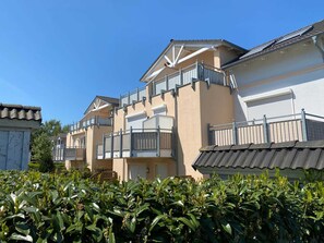 A row of residential buildings with balconies, a tiled roof, and a clear blue sky. - Strandwiese 3 Vacation Apartment (Graal-Müritz)