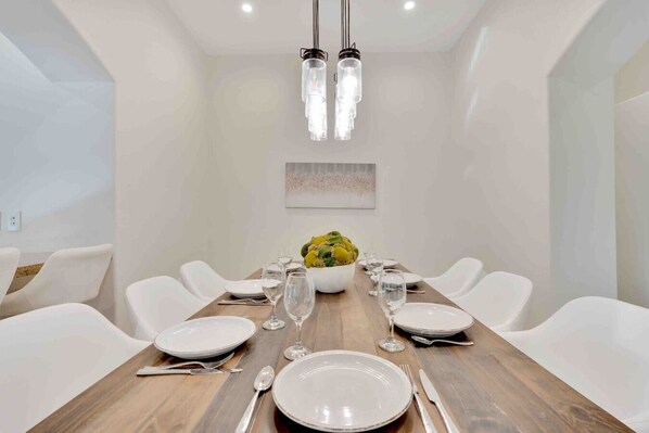 Un comedor moderno con una mesa de madera, sillas blancas y un centro de mesa con flores amarillas.