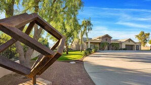 A residential area with a driveway leading to a house with a stone facade and a garage. - Specials! Heated pool+spa|Game room|Sports courts (Thousand Palms)