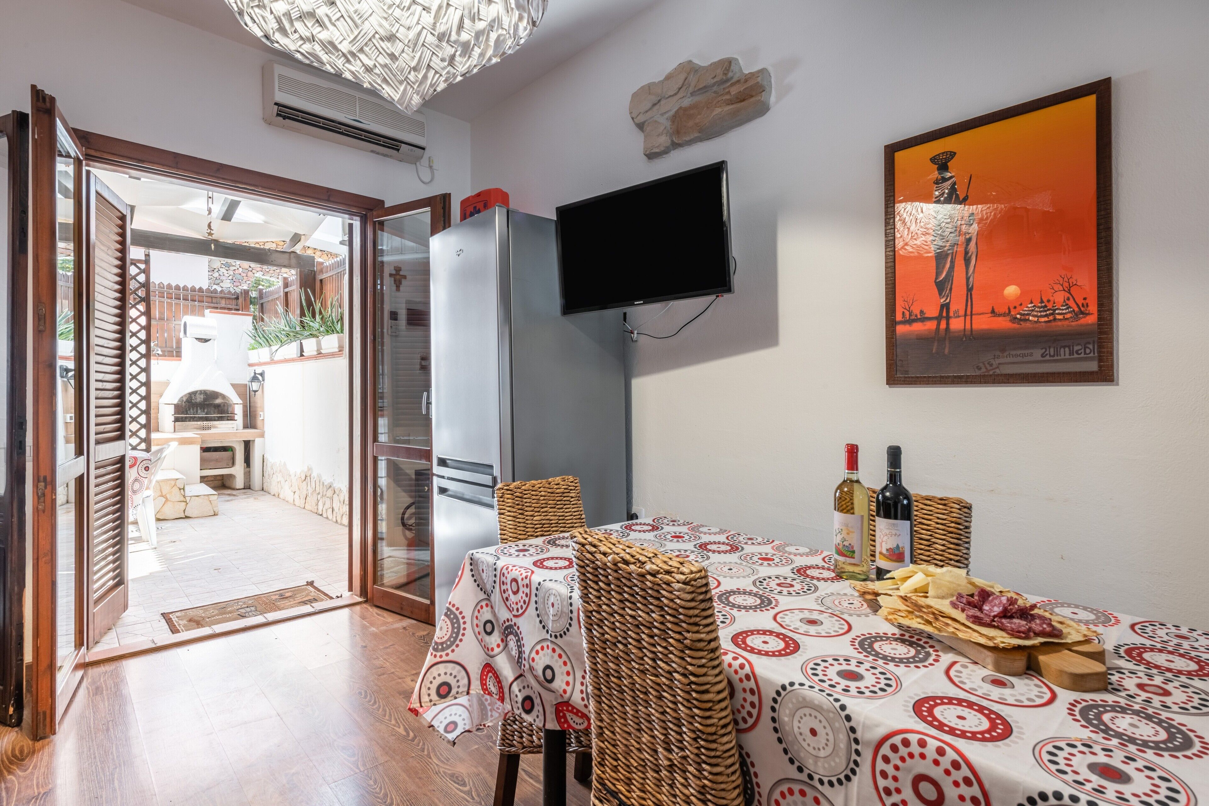 Un espace de vie à aire ouverte comprenant une table à manger, des chaises, un téléviseur et donnant sur une terrasse extérieure.