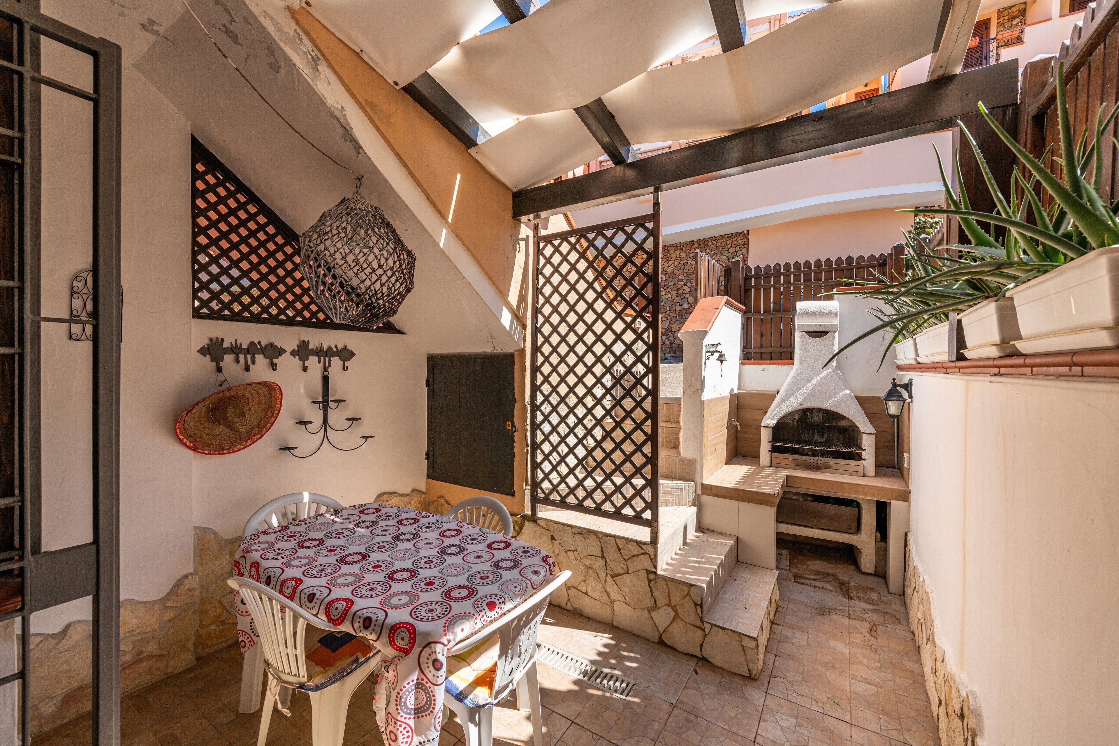 Une terrasse avec une table et des chaises, un four à pizza et une plante en pot.