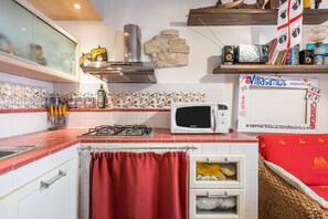 Une cuisine équipée d’un four à micro-ondes, d’une cuisinière à gaz et d’un rideau rouge.