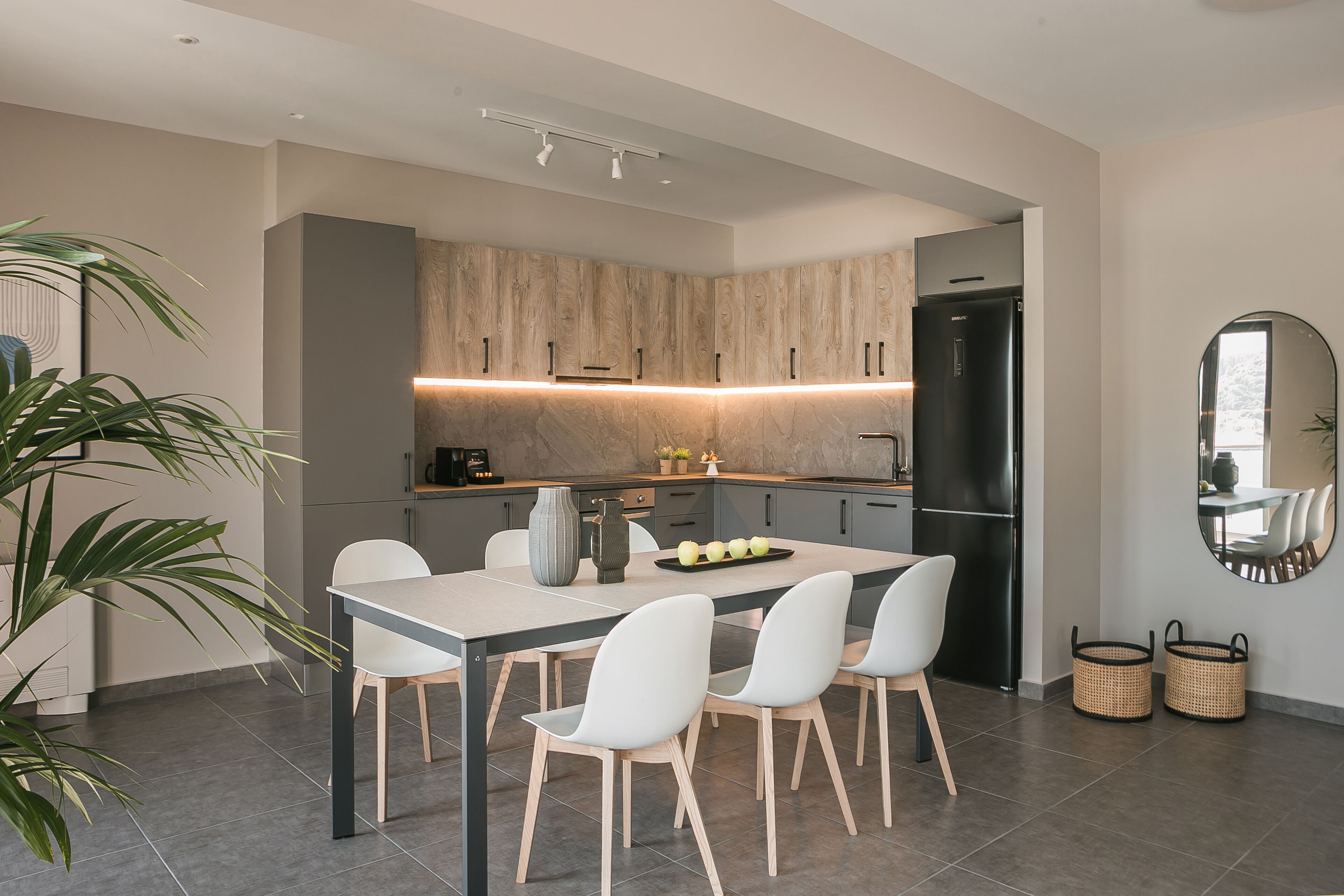 Una cocina moderna con una isla central, sillas blancas y una mesa de comedor.