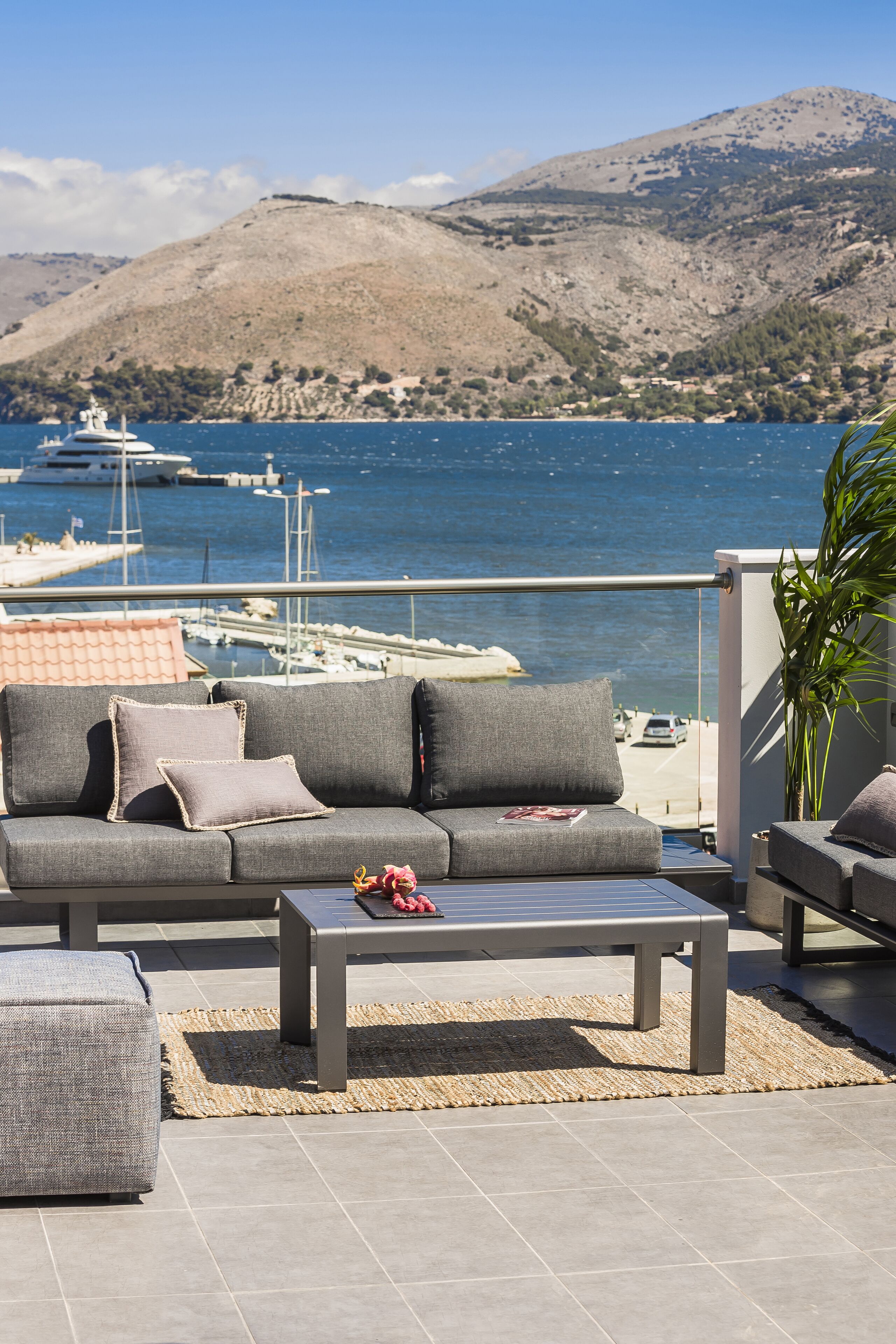 A balcony with a grey sofa, a small table, and a potted plant.