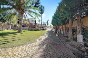 A cobblestone pathway flanked by trees and a stone wall, leading to a building with a stone facade. - 2-bed Holiday Apartment with Pool, Wi-Fi, Garden & Terrace (Armação de Pêra)