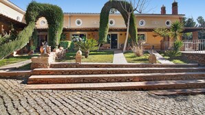 A courtyard with stone steps leading to a building with a tiled roof and arched doorways.