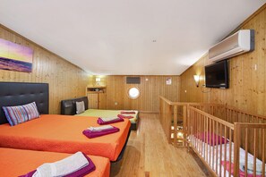 Una habitació d'hotel amb dos llits, televisió, una taula petita i un balcó.