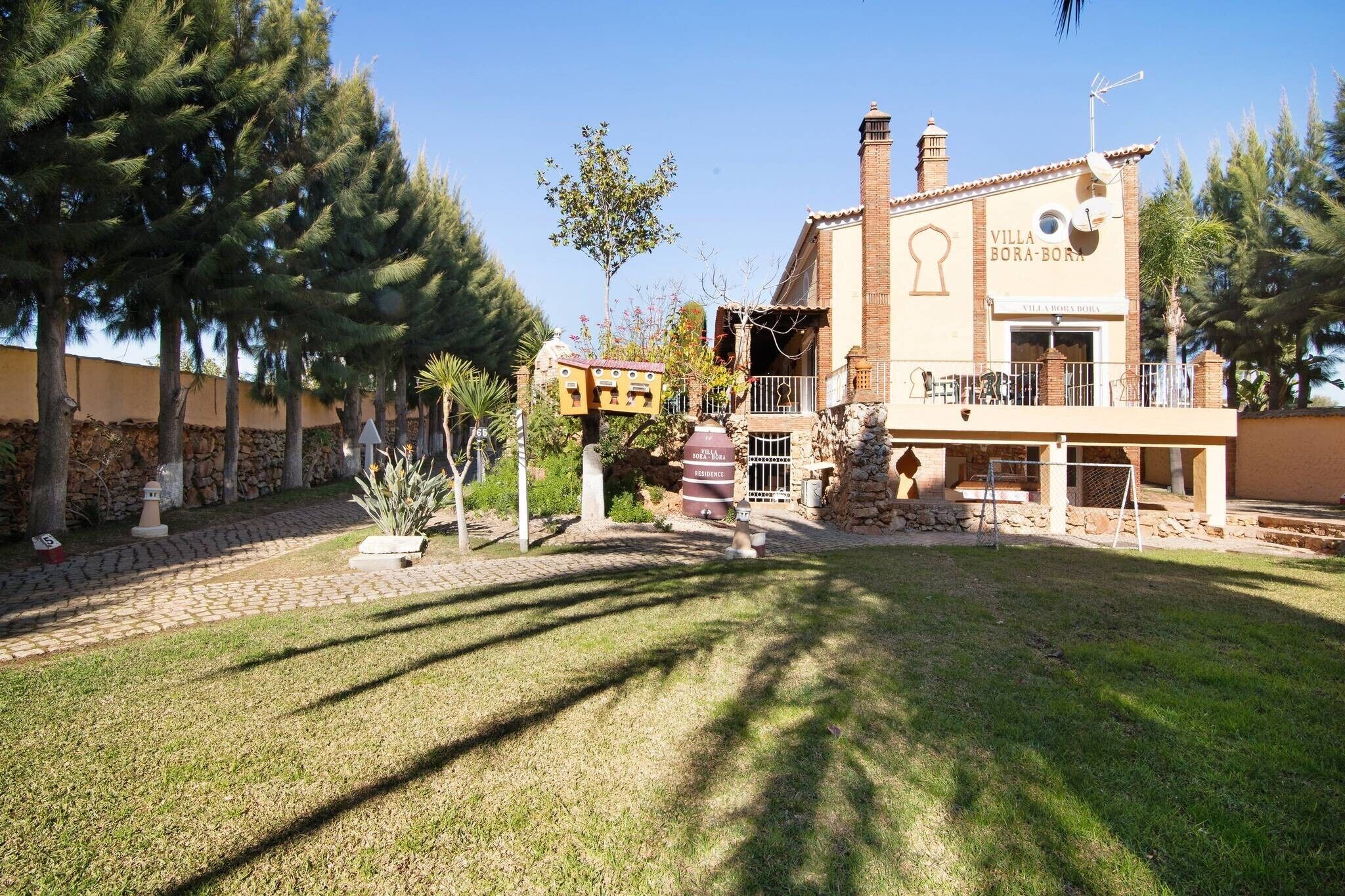 A villa with a stone facade, a balcony, and a well-maintained garden.