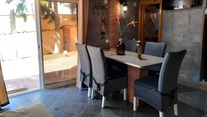 Een eetruimte met een tafel, stoelen, een televisie en uitzicht op de omgeving.