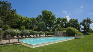 A rectangular swimming pool with a stone wall and a grassy lawn. - Agriturismo Il Forno with Mountain View, Shared Pool and Wi-Fi (Grassina)