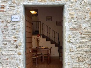 A stone-walled entrance with a staircase leading to an upper floor.