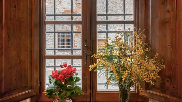 A wooden door with a window, a potted plant with red flowers, and a vase with yellow flowers. - Agriturismo Il Forno with Mountain View, Shared Pool and Wi-Fi (Grassina)