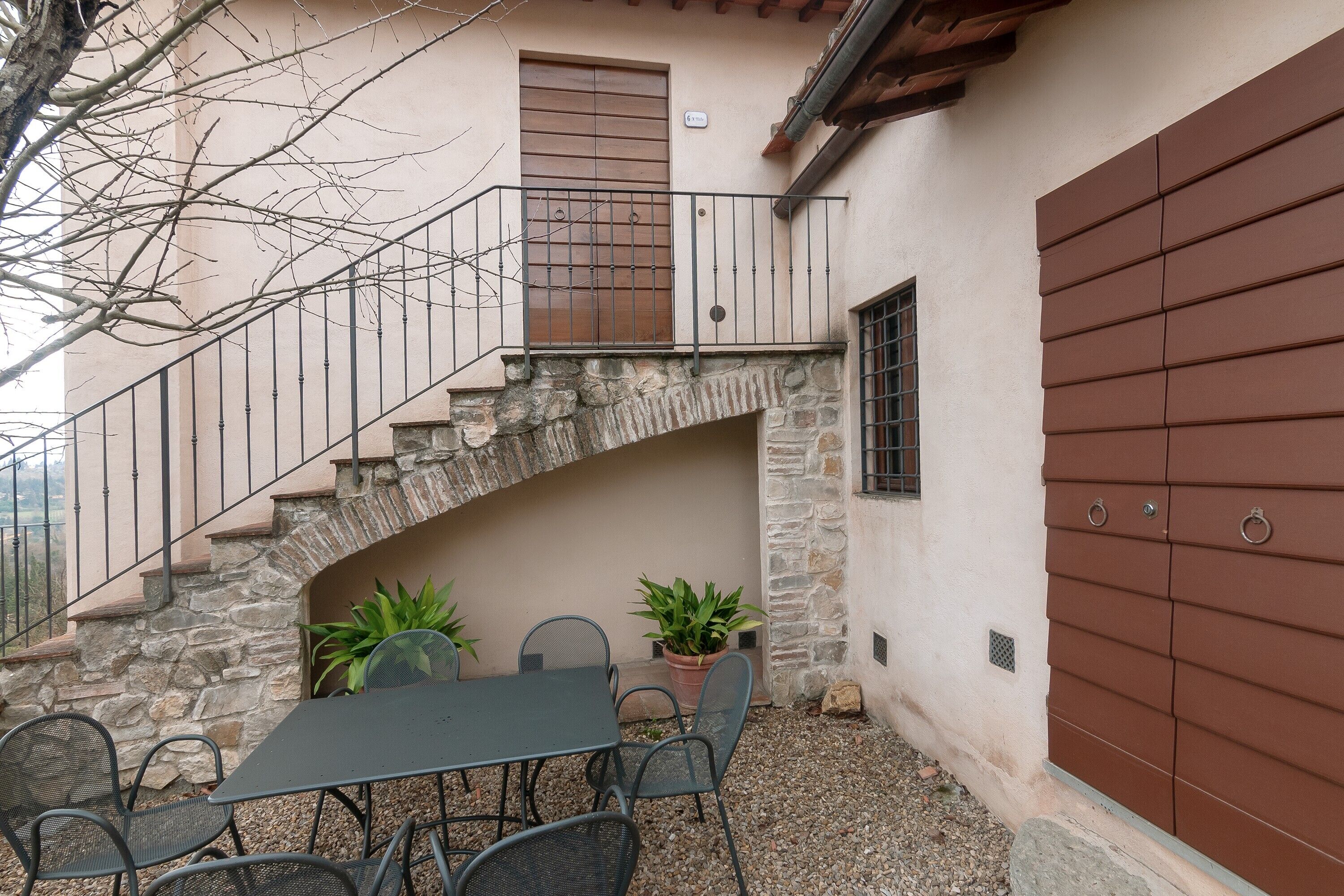 A patio with a table and chairs, a stone staircase, and a brown door.