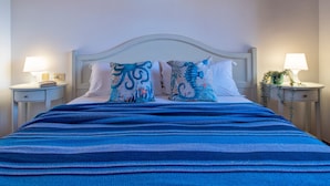 A bed with a blue striped bedspread, two decorative pillows, a white headboard, and two bedside tables with lamps and small decorative items. - Villa "Azzurra" with Sea View, Pool and Garden (Stintino)