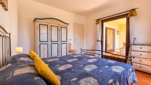 Een slaapkamer met een bed, een kledingkast, een stoel en een dressoir.