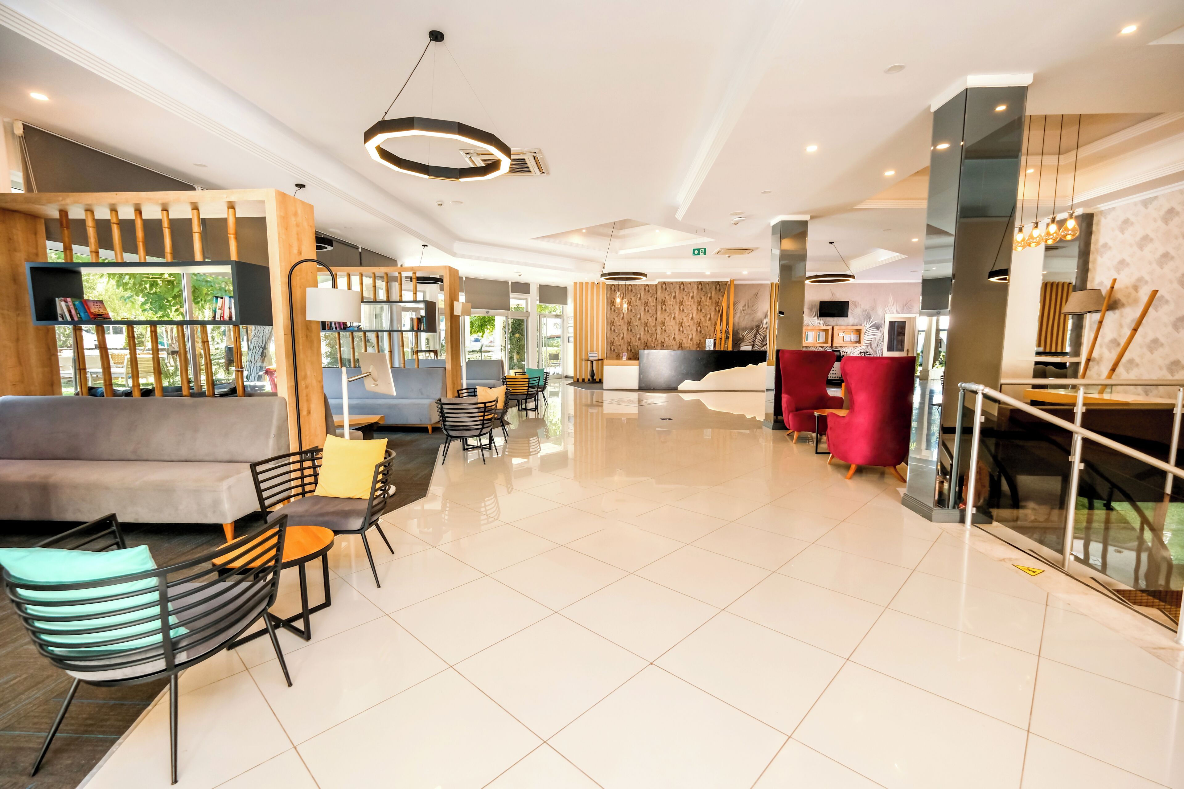 A modern hotel lobby with a reception desk, seating area, and a staircase.