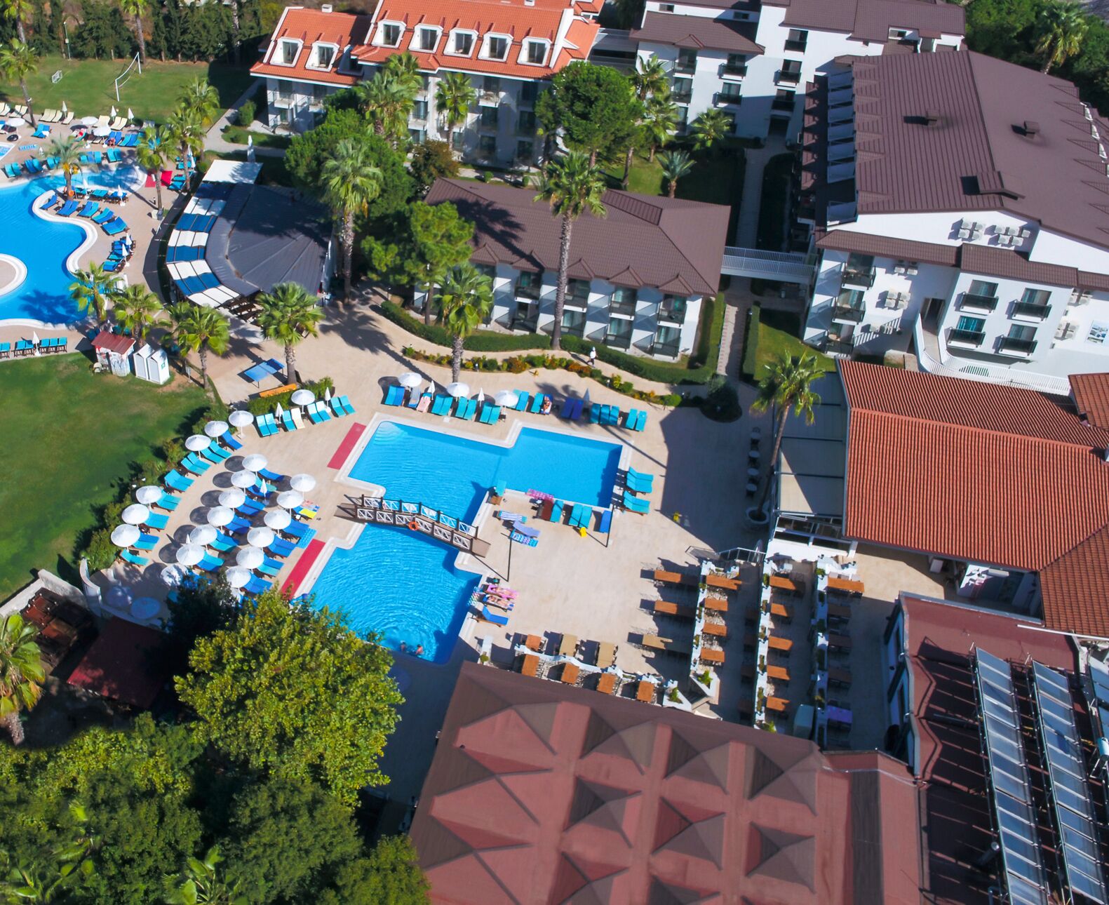 A resort with multiple swimming pools, sun loungers, and palm trees.