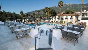 Un área de piscina en la azotea con mobiliario exterior y vistas a montañas.