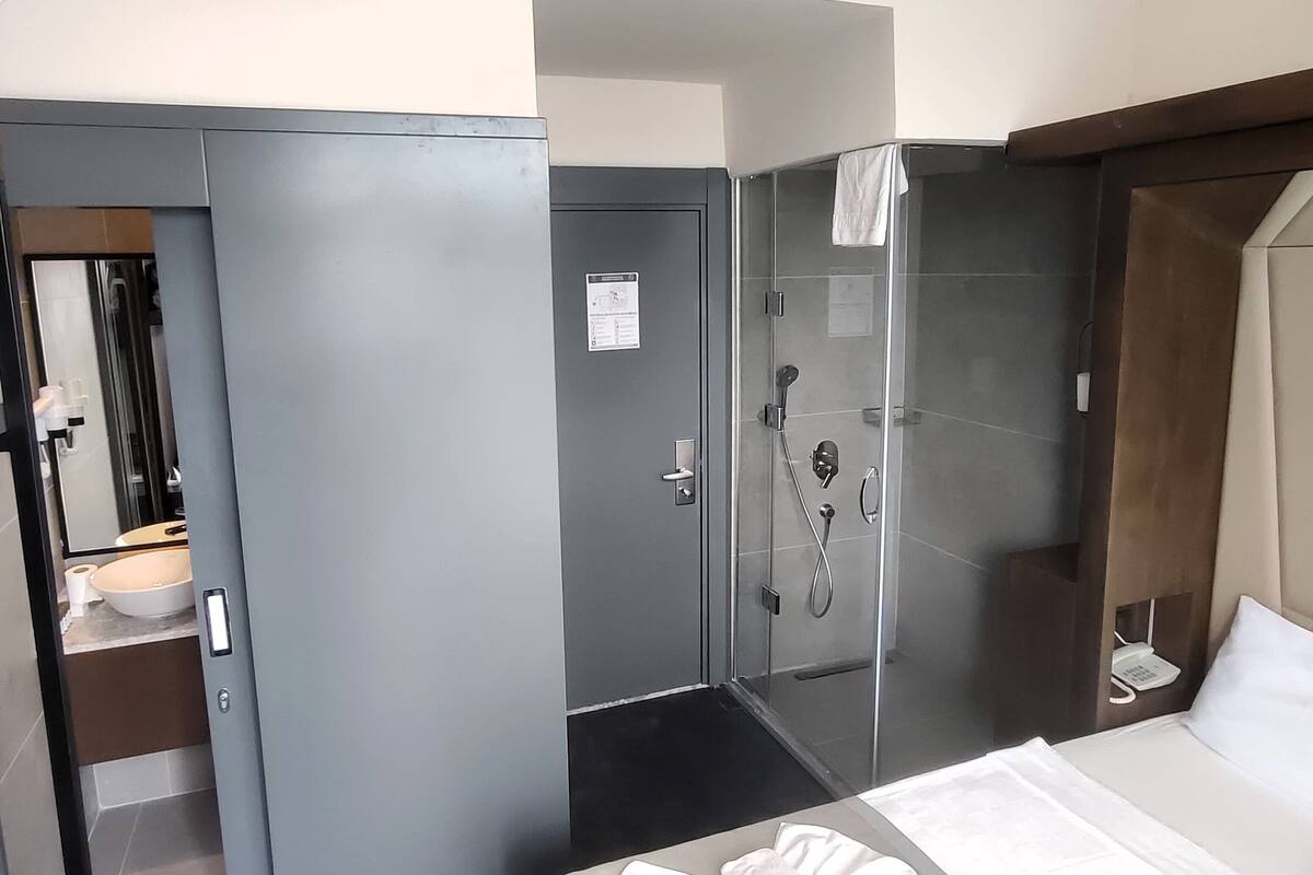 A hotel room with a bed, a bathroom with a shower, and a toilet.