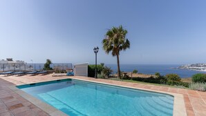 Piscina com vista para o oceano, uma palmeira e um poste de luz.