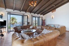 A spacious living area with leather sofas, a round coffee table, and a television. - Villa Las Dalias Almunecar and Nerja (Almunecar)