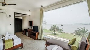 Ein Hotelzimmer mit Bett, einer Couch, einem Fernseher und Blick aufs Meer.