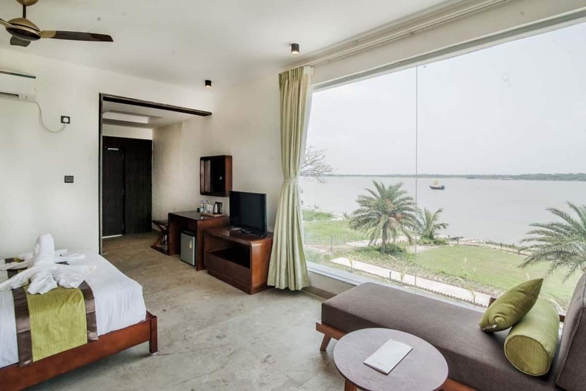 A hotel room with a bed, a sofa, a TV, and a view of the sea.