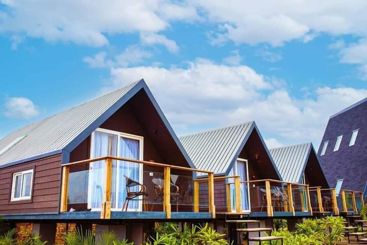 A row of modern, triangular-roofed cabins with wooden balconies and large windows.
