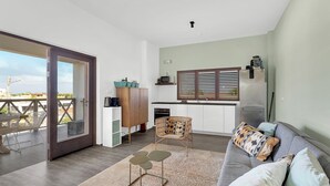 Un espacio de estar moderno con sofá, mesa de comedor y zona de cocina.