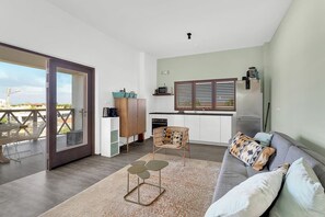 A modern living space with a sofa, a dining table, and a kitchen area. - Belnem Breeze Tres with a mature palm garden and refreshing shared pool (Kralendijk)