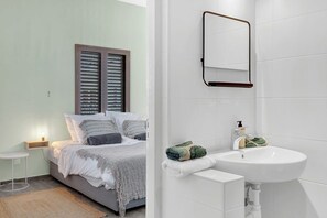 A bedroom with a bed, bedside table, and a window with blinds.