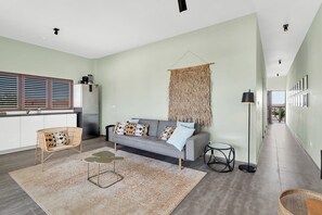 A modern living room with a sofa, a coffee table, and a floor lamp. - Belnem Breeze Tres with a mature palm garden and refreshing shared pool (Kralendijk)
