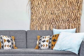 A grey sofa with patterned cushions and a textured wall behind it. - Belnem Breeze Tres with a mature palm garden and refreshing shared pool (Kralendijk)