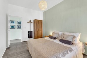 A bedroom with a bed, a wardrobe, a floor lamp, and a wall-mounted TV. - Belnem Breeze Tres with a mature palm garden and refreshing shared pool (Kralendijk)