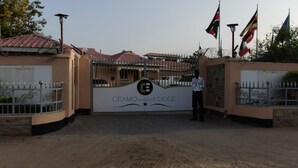 The entrance to CEAMO Prestige Lodge with a gated driveway, security personnel, and flags. - Ceamo Prestige Lodge (Makutano)