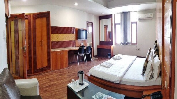 Una habitación de hotel con cama, escritorio, silla, televisor y armario.