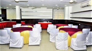 Un salón de conferencias con mesas redondas, manteles blancos y amarillos y sillas blancas.