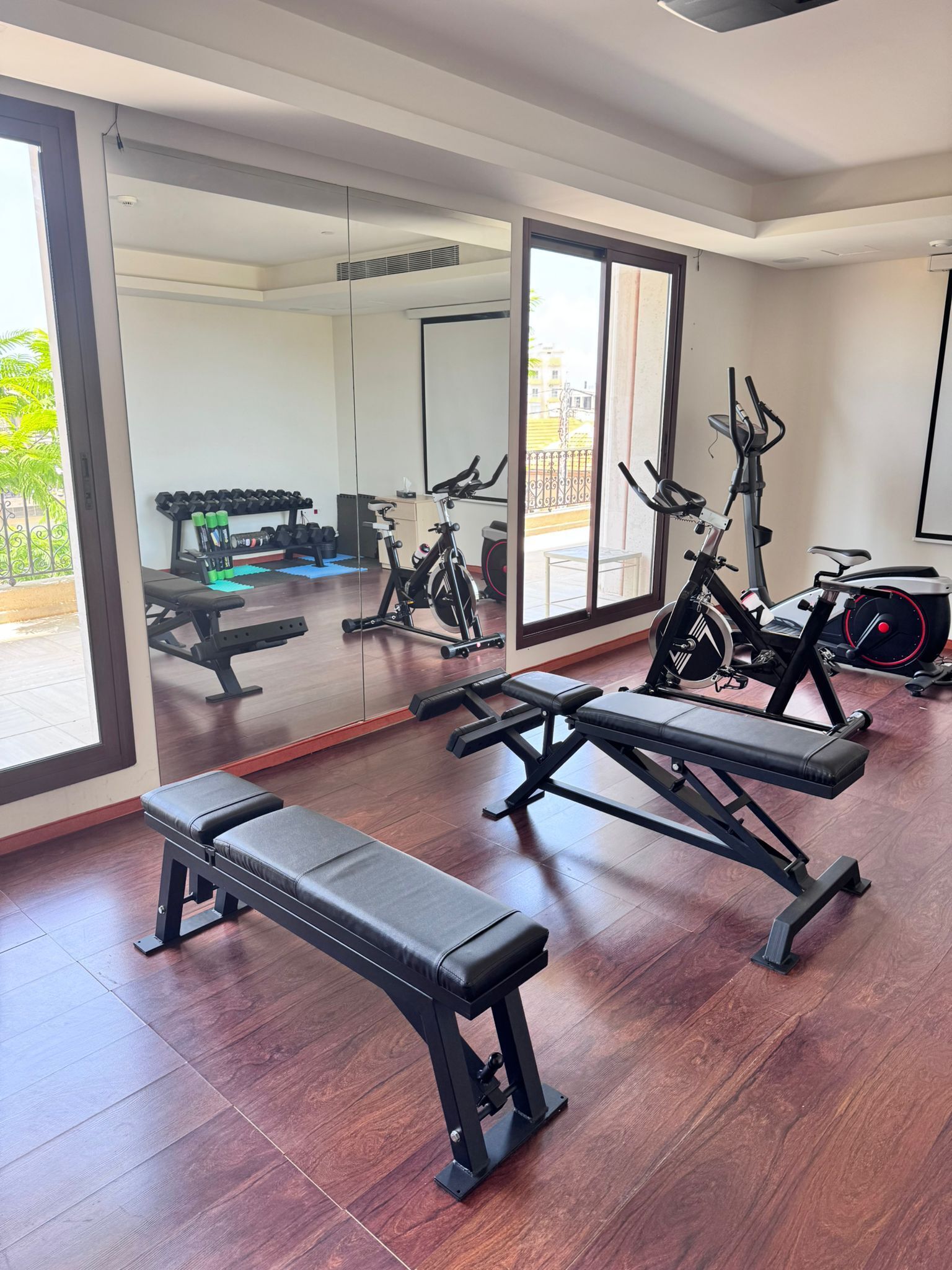 A gym with exercise equipment, a bench, and a large mirror.