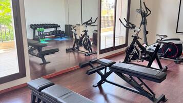 A gym with exercise equipment, a bench, and a large mirror.