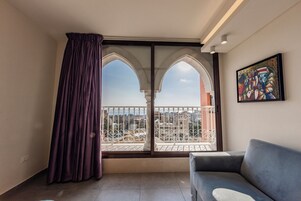 Uma varanda com vista para a cidade, um sofá azul e um quadro na parede.