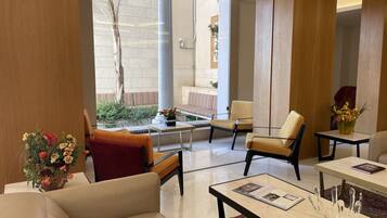 Un hall moderno con un sofá, sillas, una mesa de centro y vistas al exterior.