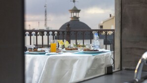 Een tafel met eten en drinken op een balkon, met uitzicht op een gebouw en een koepel.