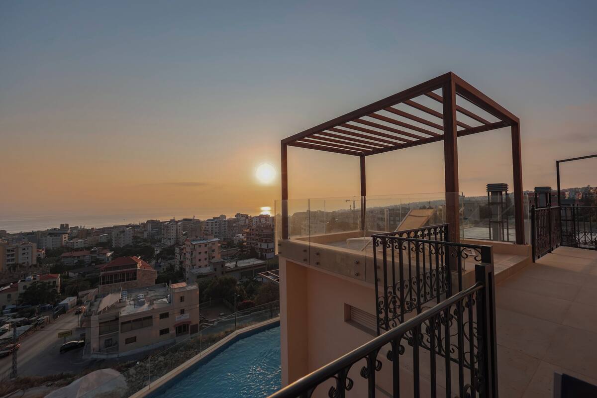 A balcony with a view of a cityscape and a swimming pool.