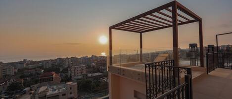 A balcony with a view of a cityscape and a swimming pool.