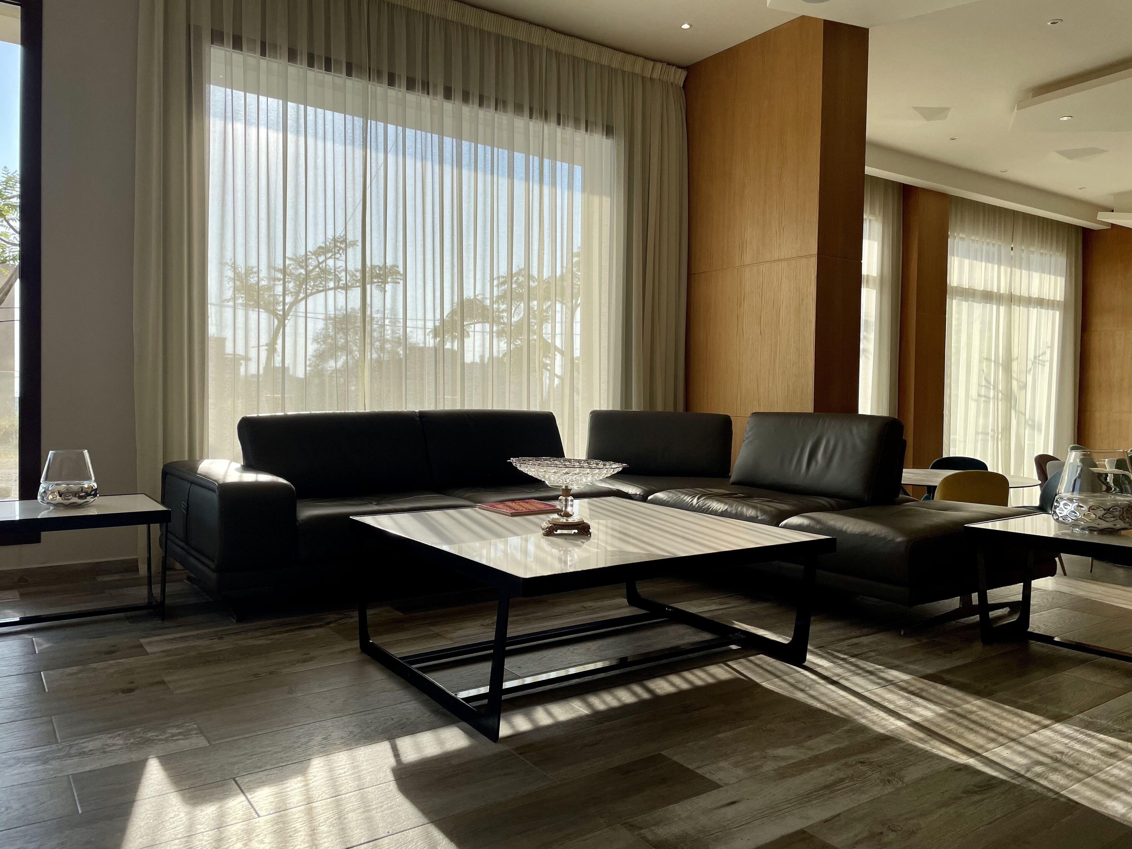 Una sala de estar moderna con un sofá, una mesa de centro y vistas al exterior a través de amplios ventanales.