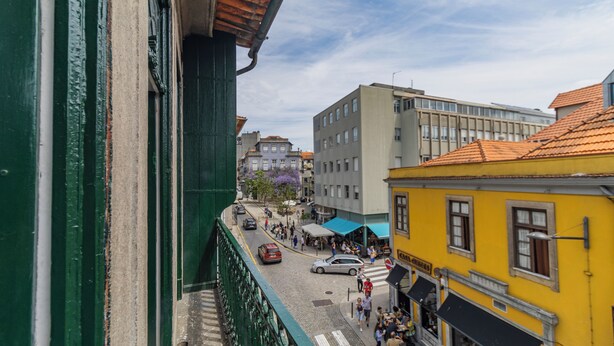 A street view with buildings, a café, and pedestrians. - Invictus Hostel (Porto)